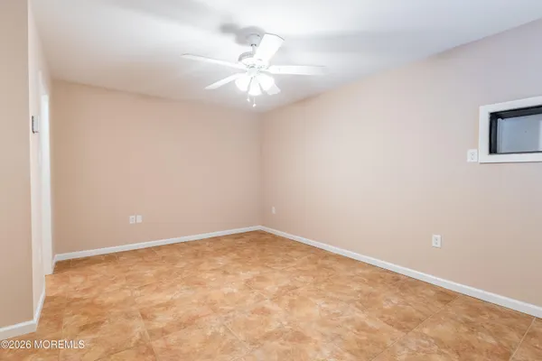 an empty room with a fan & a window