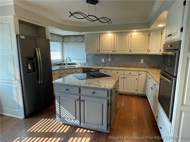 a kitchen with stainless steel appliances granite countertop a sink a stove a refrigerator and cabinets