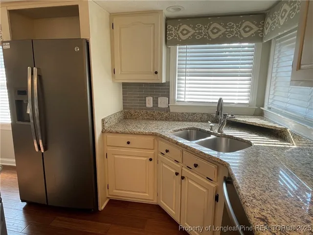 a kitchen with granite countertop a sink and a refrigerator