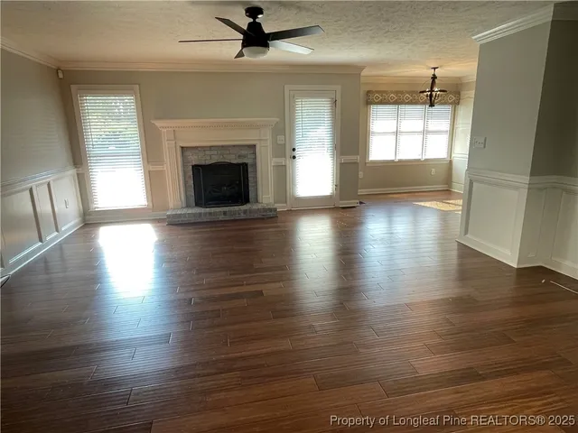 an empty room with wooden floor fireplace and windows