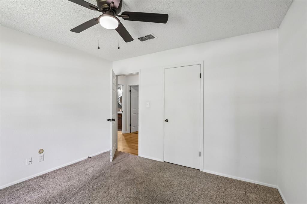 1600 South Timber Court Benbrook, TX 76126 - Photo 14 of 30 Neutral white walls with textured ceiling and a dark-toned ceiling fan