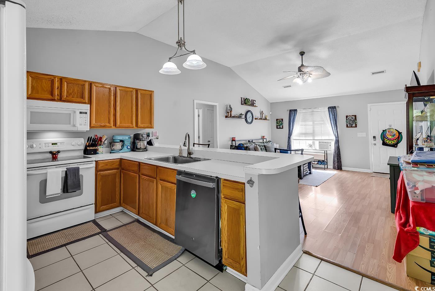 9450 Leeds Circle Myrtle Beach, SC 29588 - Photo 8 of 25 Kitchen featuring a peninsula, vaulted ceiling, a sink, and white appliances