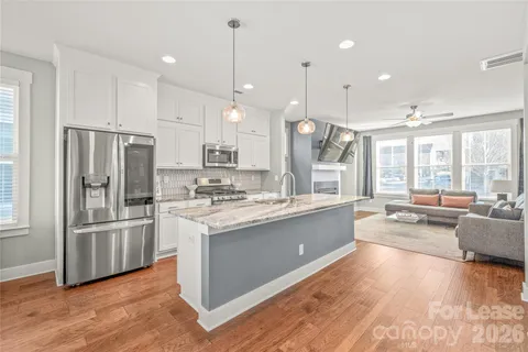a large kitchen with kitchen island a stove a sink a center island and wooden floor