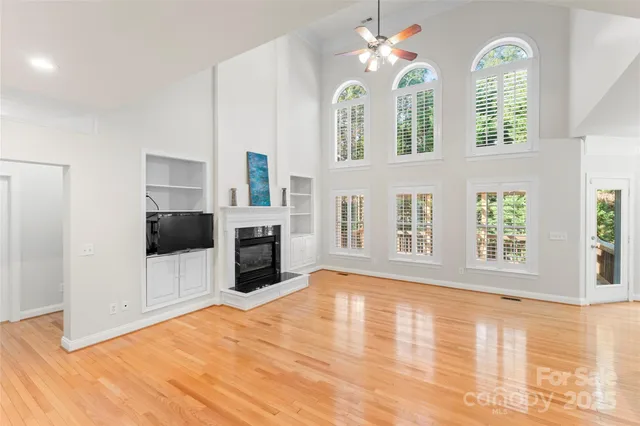 a living room with stainless steel appliances kitchen island granite countertop a refrigerator a stove top oven a sink dishwasher and wooden cabinets with wooden floor