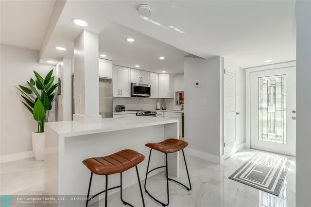 a kitchen with stainless steel appliances kitchen island granite countertop a refrigerator and a stove top oven with white cabinets