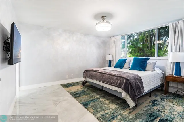 a bedroom with a bed and a flat tv screen on dresser