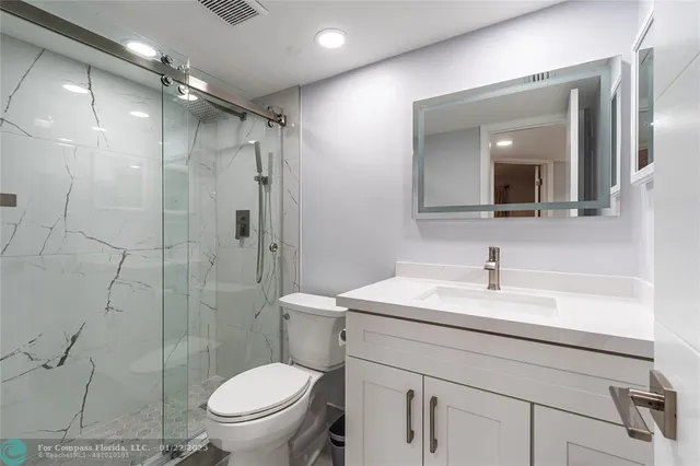 a bathroom with a sink toilet vanity and shower