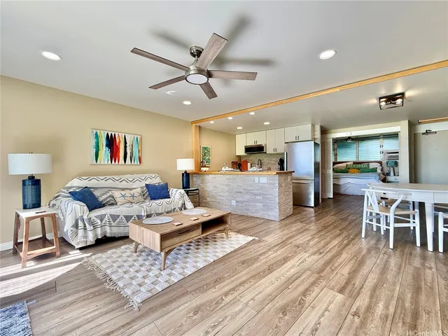 a living room with furniture kitchen view and a wooden floor