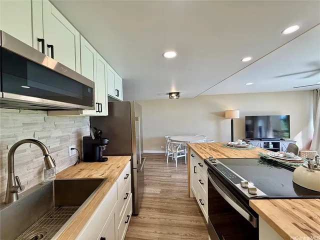 a kitchen with kitchen island stainless steel appliances a sink stove and refrigerator