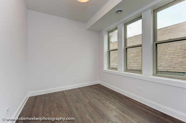 2329 West Barry Avenue, Unit 2 Chicago, IL 60618 - Photo 6 of 10 a view of an empty room with wooden floor and a window