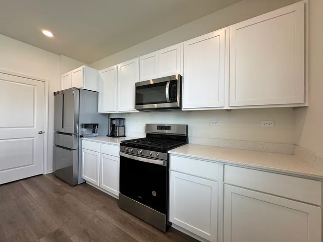 a kitchen with stainless steel appliances granite countertop white cabinets sink and a refrigerator