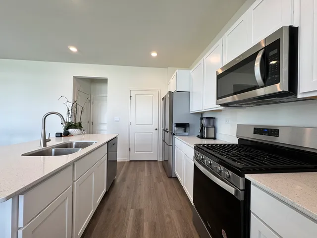 a kitchen with stainless steel appliances a sink a stove top oven a refrigerator cabinets and a sink