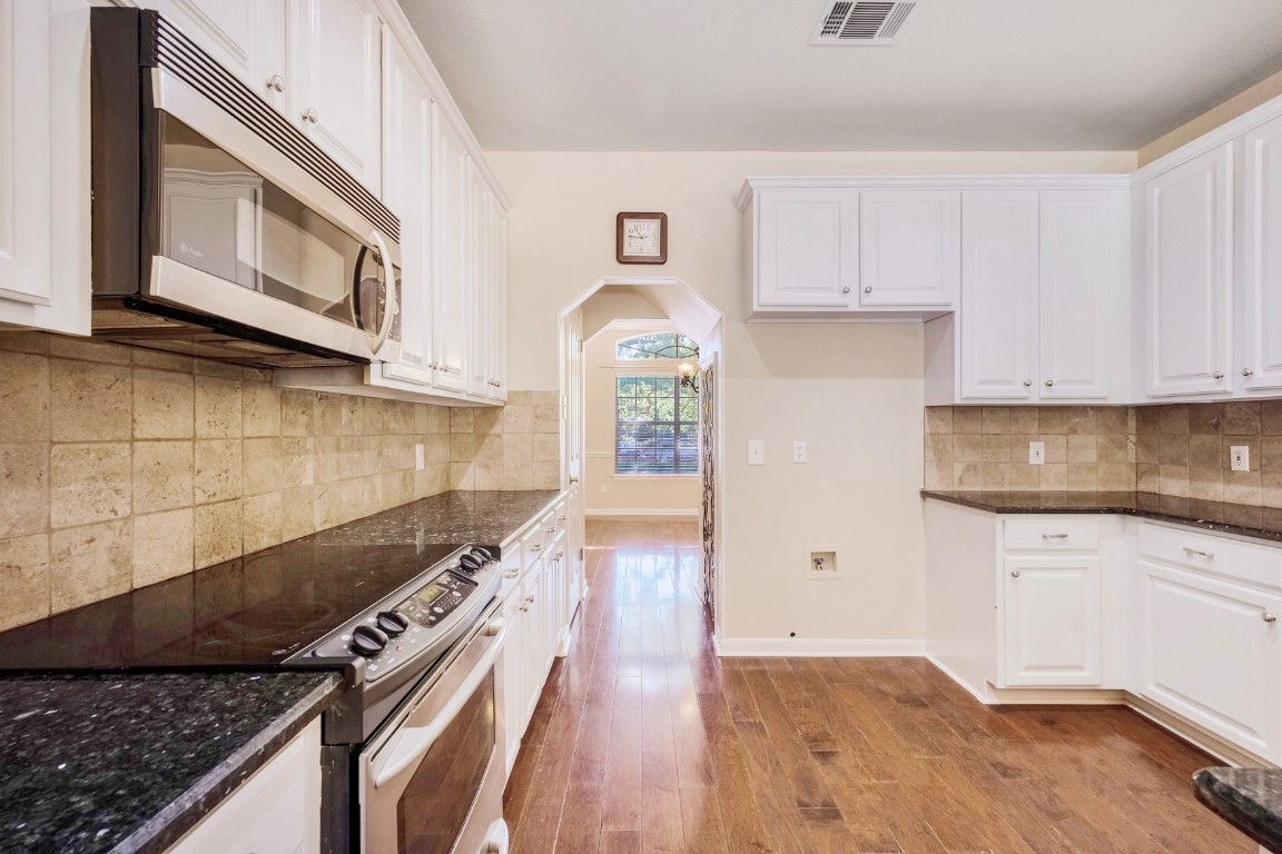 30103 Wingfoot Cove Georgetown, TX 78628 - Photo 13 of 38 a kitchen with granite countertop a stove and a white cabinets