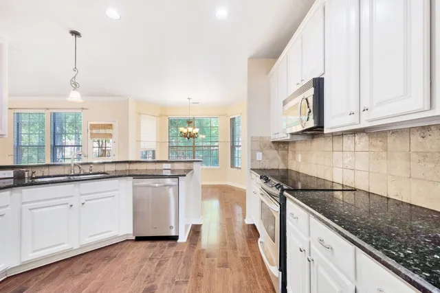 a kitchen with stainless steel appliances granite countertop a sink a stove and a wooden floors