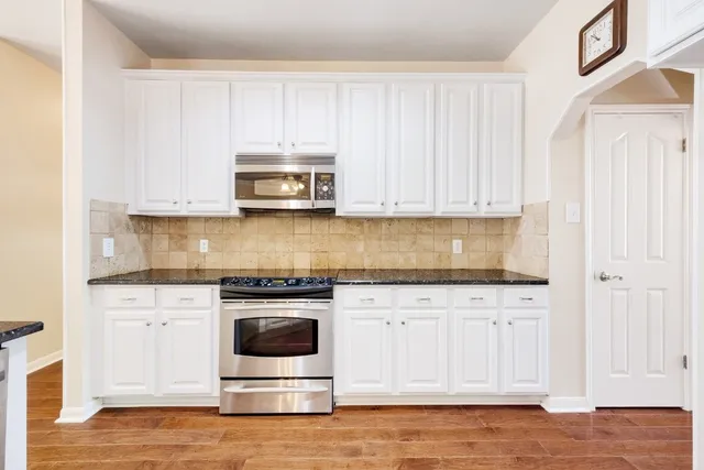 a kitchen with granite countertop white cabinets and stainless steel appliances