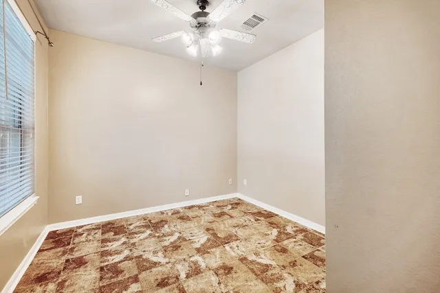 an empty room with a window and ceiling fan