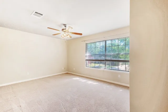 an empty room with a window and a ceiling fan