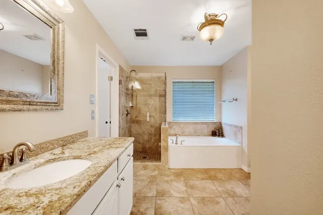 a bathroom with a granite countertop sink a mirror and bathtub