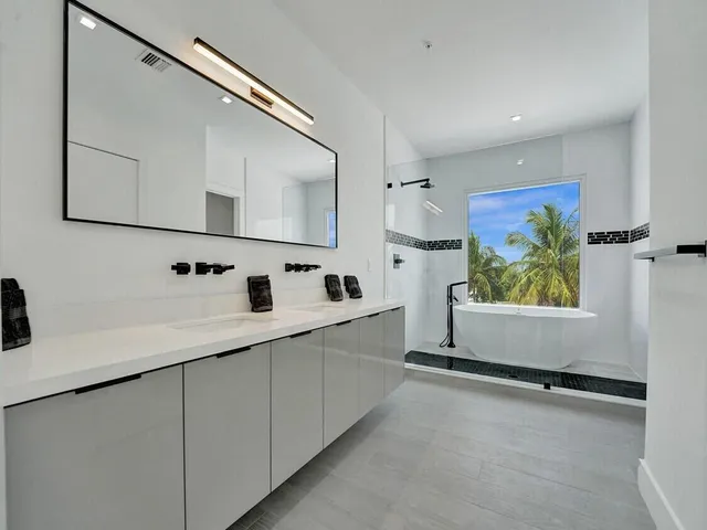 a large white kitchen with kitchen island a sink stainless steel appliances and cabinets