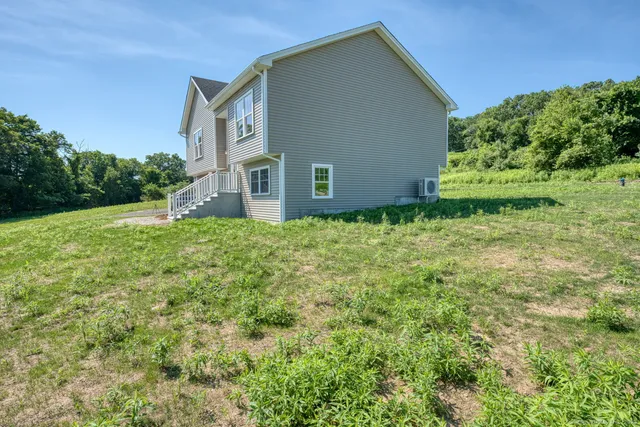a backyard of a house with plants and large tree