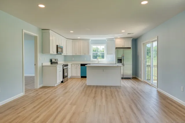 a kitchen with wooden floors and white stainless steel appliances