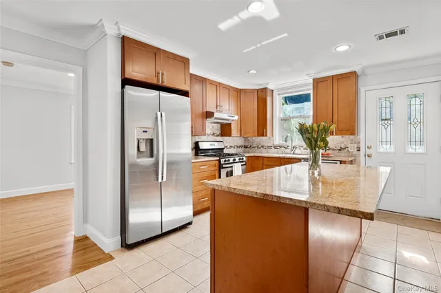 a kitchen with stainless steel appliances granite countertop a refrigerator a stove and a sink with granite countertops