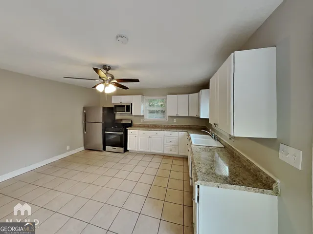 a kitchen with granite countertop a stove a sink and a refrigerator