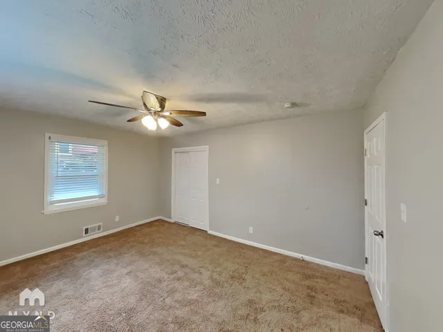 an empty room with a window and a fan