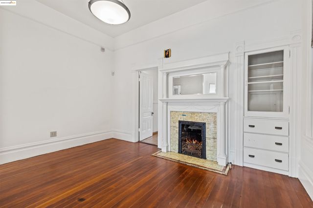 an empty room with wooden floor fireplace and windows