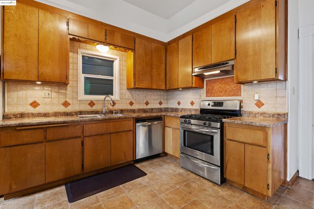 a kitchen with stainless steel appliances granite countertop a stove a sink and a refrigerator