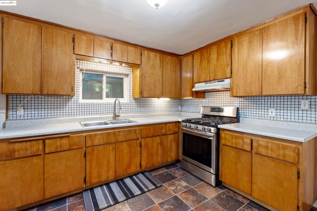 a kitchen with granite countertop a sink a stove and refrigerator