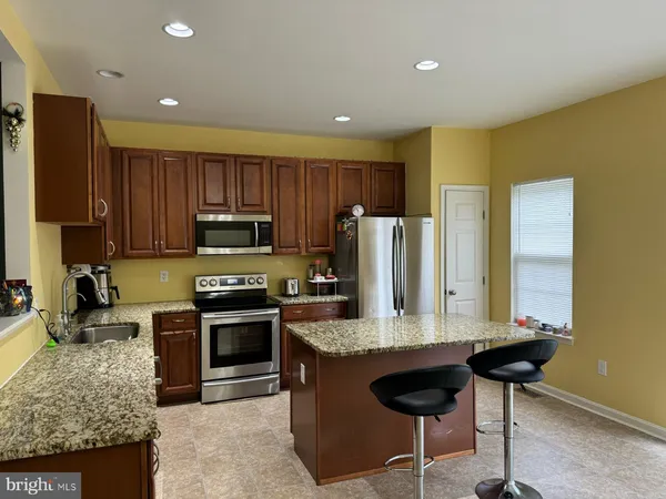 a kitchen with granite countertop wooden cabinets a stove a oven a refrigerator and a oven