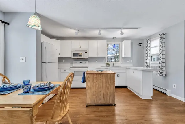 a kitchen with stainless steel appliances granite countertop a stove a sink dishwasher a refrigerator white cabinets and wooden floor