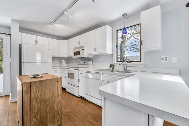 a kitchen with a sink a stove a refrigerator and white cabinets