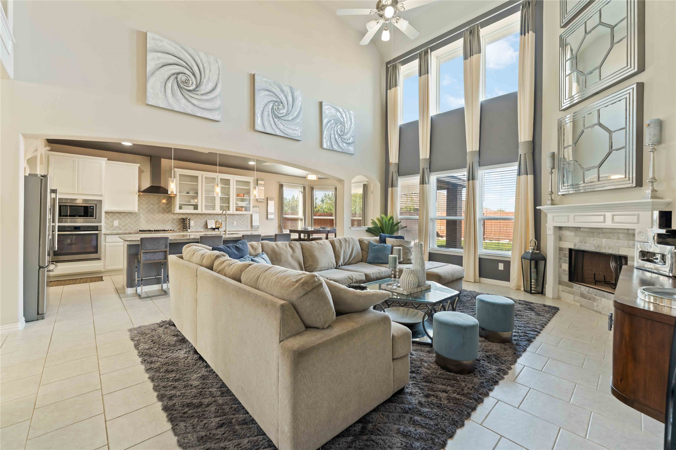 7403 Dry Stone Lane Rosenberg, TX 77469 - Photo 2 of 19 Welcome Home! This spacious living area features over 20 ft ceilings and large windows that provide ample natural light. The open-plan design connects seamlessly with a sprawling kitchen equipped with all stainless steel appliances. The gas fireplace and cleanly painted neutral tones create a warm and inviting atmosphere, perfect for entertaining or relaxing.