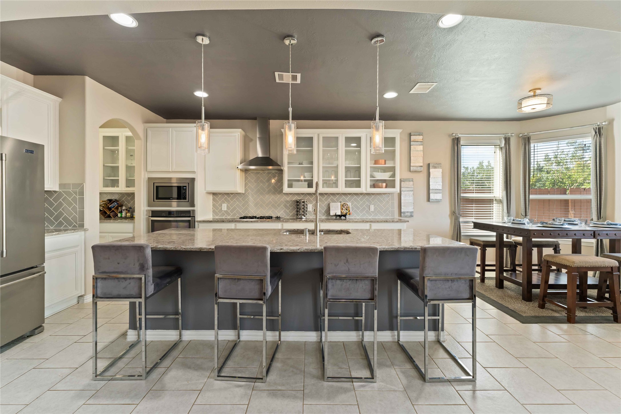 7403 Dry Stone Lane Rosenberg, TX 77469 - Photo 7 of 19 Open-concept kitchen anchored by a large island with bar seating, pendant lighting, and over 10 ft of counter space. The layout is ideal for gatherings while maintaining functionality and connection to the living and dining spaces.