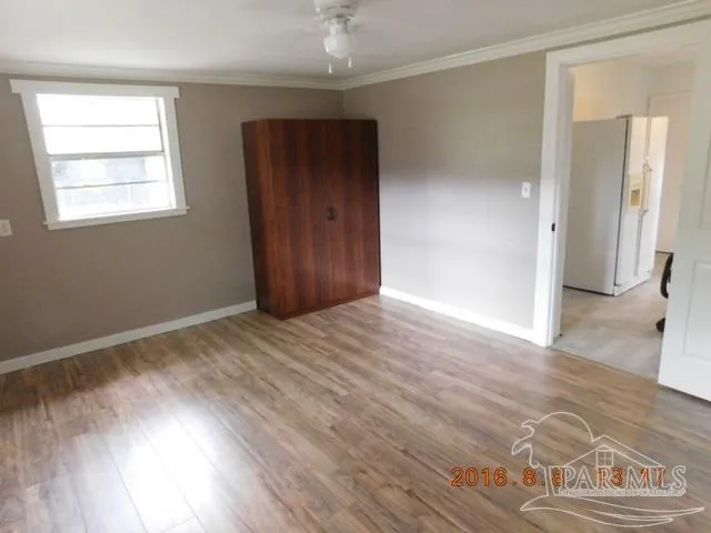 an empty room with wooden floor cabinet and windows