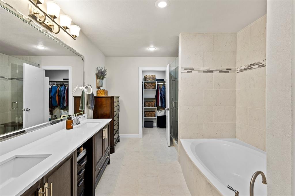 668 Cleve Cole Road Denison, TX 75021 - Photo 15 of 38 Bathroom featuring a dual vanity with white countertops, expansive wall mirror, built-in bathtub, and a glass-enclosed shower