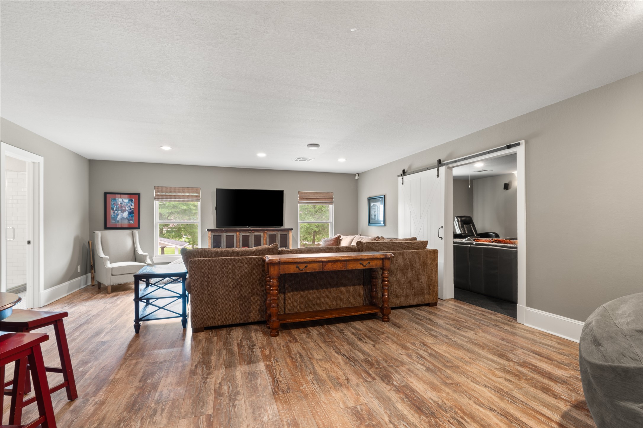 36 Wind River Drive Conroe, TX 77384 - Photo 38 of 45 This is the primary, open living room in the Living Space above the garage. This spacious living room features warm wood flooring and neutral walls. A sliding barn door leads to the media room, enhancing the home's open and inviting layout.