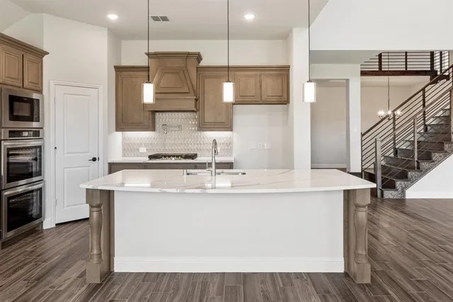 a kitchen with kitchen island stainless steel appliances a sink and a refrigerator
