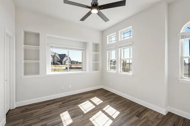 a view of empty room with wooden floor and fan