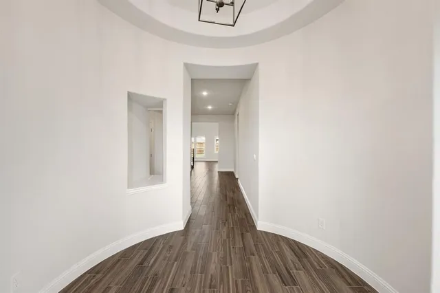 a view of a hallway with wooden floor and a bathroom