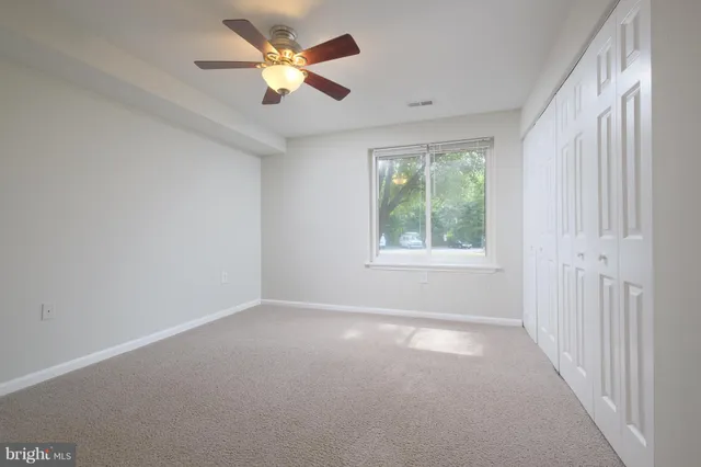 an empty room with closet and a chandelier fan