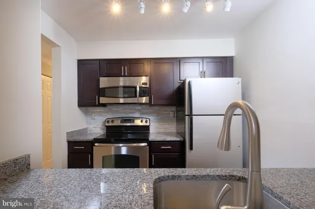 a kitchen with stainless steel appliances granite countertop a refrigerator a stove a sink and a microwave