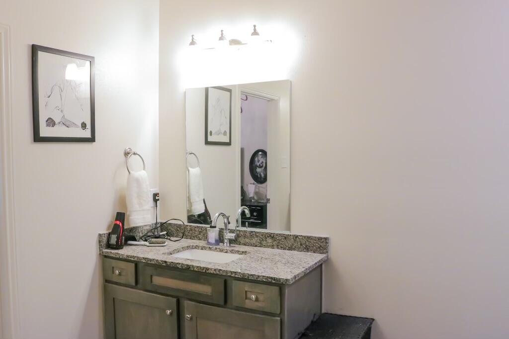5532 Kemper Street Lubbock, TX 79416 - Photo 8 of 11 a bathroom with a granite countertop sink and a mirror
