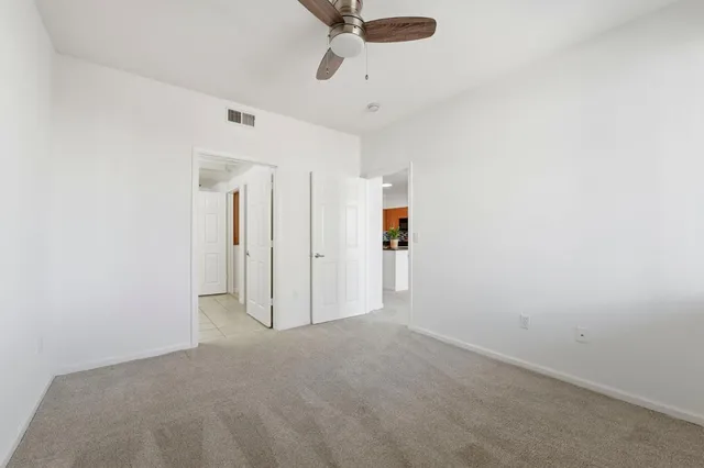 an empty room with windows and ceiling fan