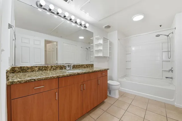 a bathroom with a granite countertop sink a mirror and a toilet