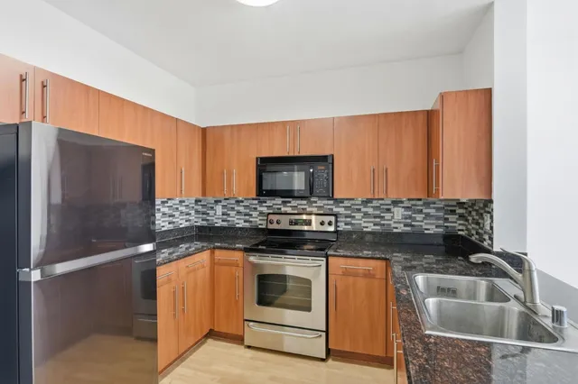 a kitchen with granite countertop a stove top oven cabinetry a sink and a granite counter top