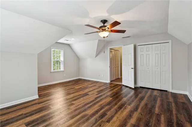 an empty room with wooden floor chandelier fan and windows