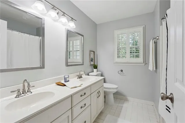 a bathroom with a double vanity sink toilet mirror and shower